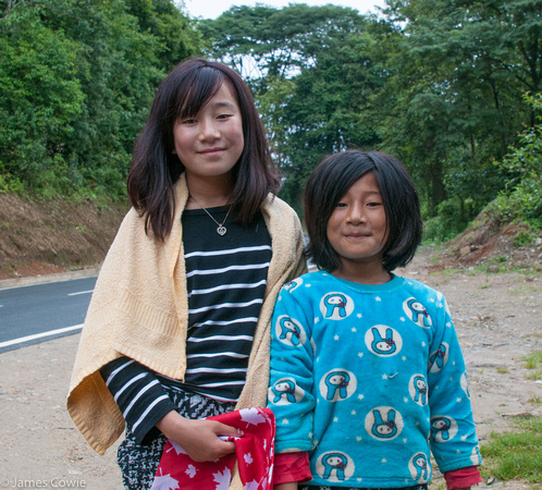 Two girls at a roadside fruit and vegi stand.