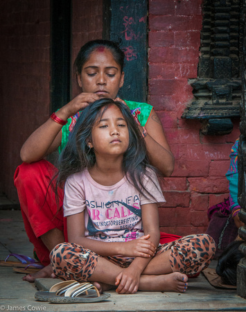 Mom doing her daughters hair on one of the sides streets of Patan Durbar Square.